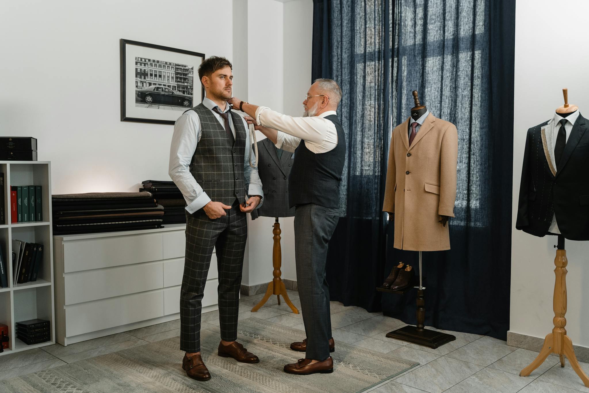 Experienced tailor adjusting a young man's stylish suit in a sophisticated atelier setting.