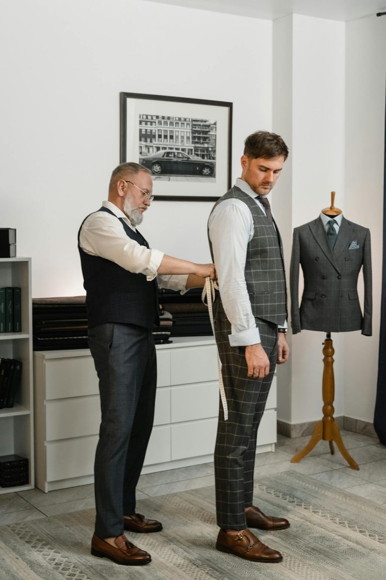 Expert tailor fitting a client's designer suit in a luxury atelier setting.