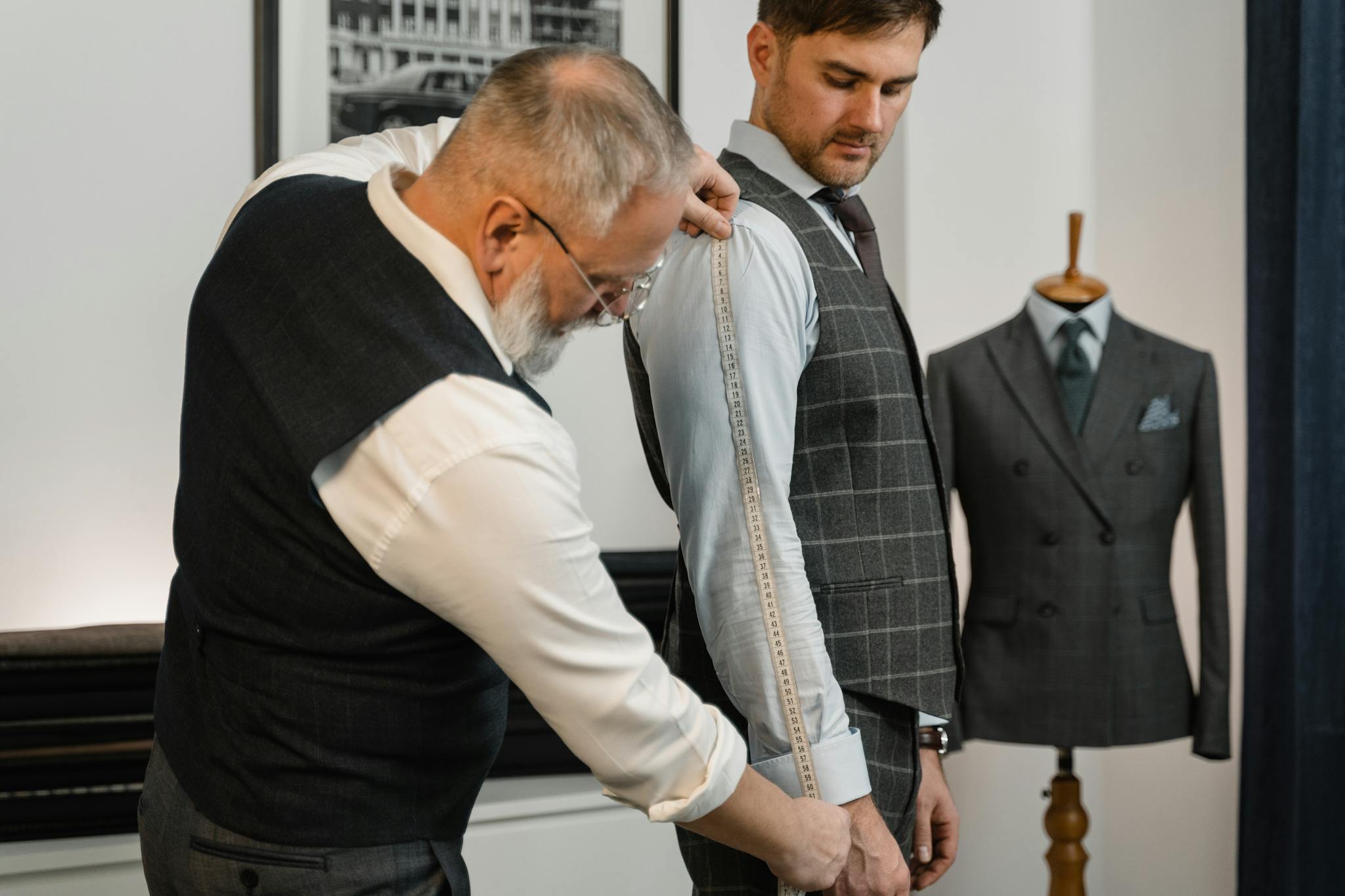 Professional tailor measuring client for a bespoke suit in a modern atelier.